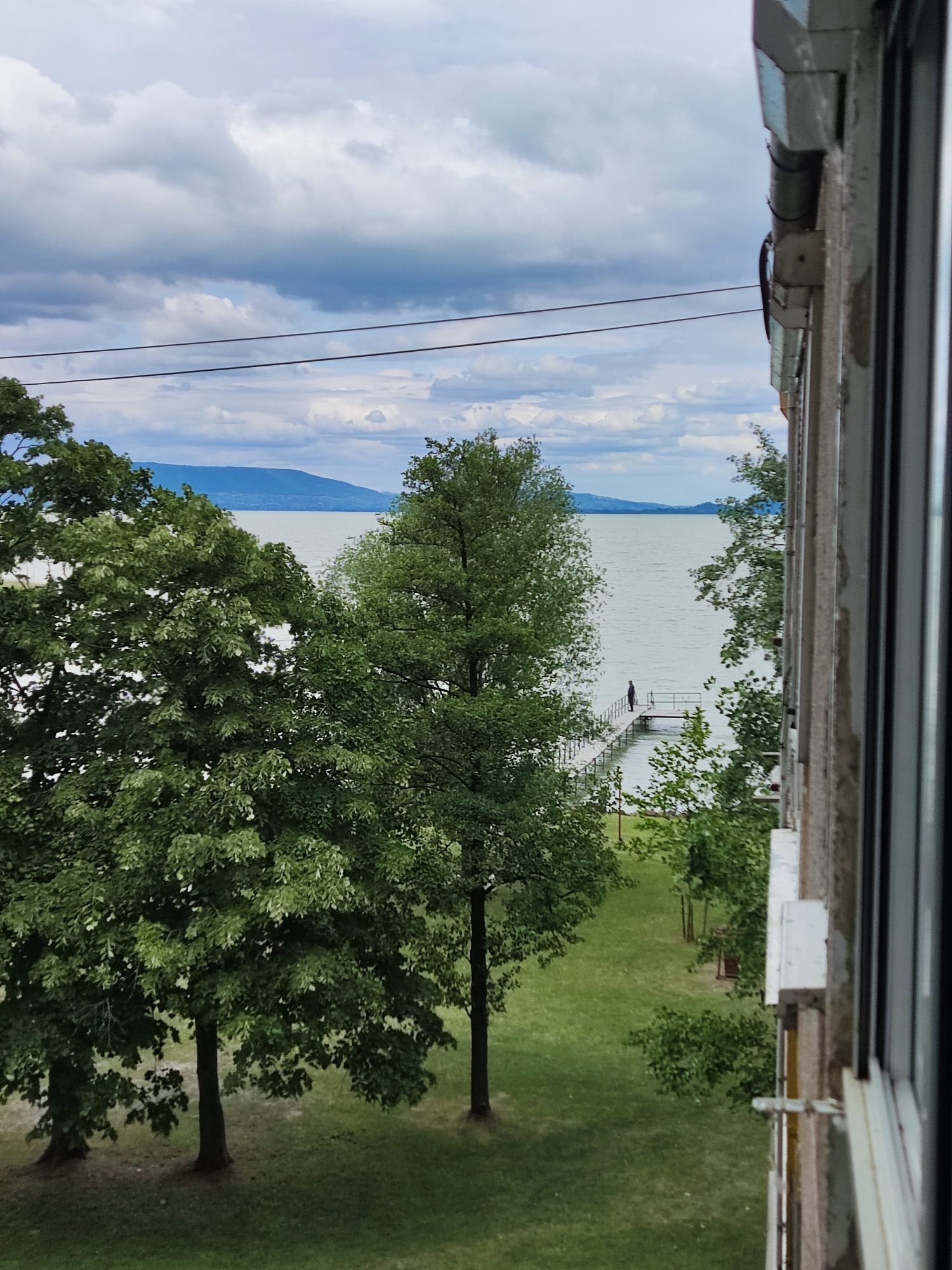 Kilátás az apartman ablakából a fák fölött a Balatonra és a stégre