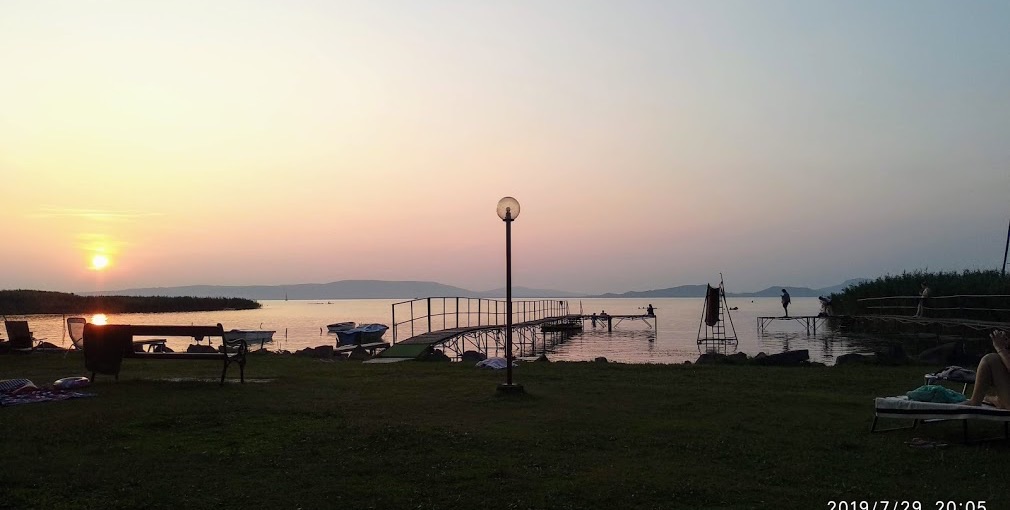 Naplemente a szálláshely partjáról: a lenyugvó nap aranyhidat rajzol a Balaton vizére
