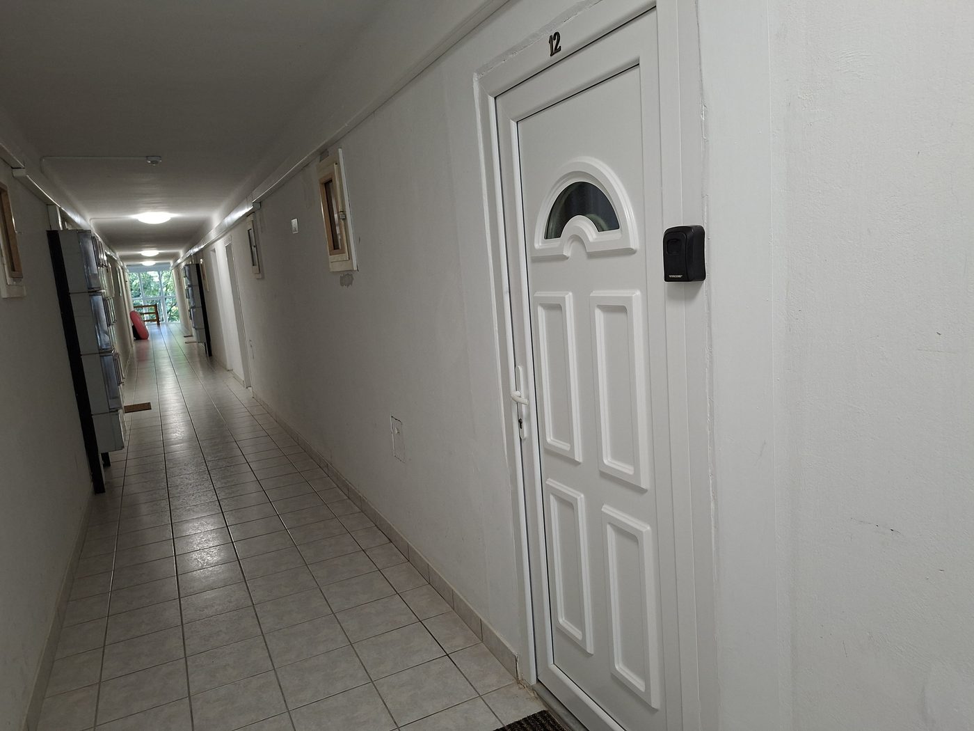 Az apartman bejárati ajtaja a folyosón, mellette a falra szerelt fekete kulcsszéf